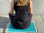 Woman sitting on a turquoise and grey acupressure mat